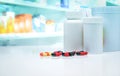 Capsule pills with drug bottles on white counter on blurred drug display shelf in pharmacy. Pharmacy shop background. Royalty Free Stock Photo