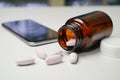 Capsule pills spill out brown bottles and mobile smartphone telephone on blurry background. Royalty Free Stock Photo