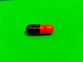 A capsule tablet isolated in a green background Royalty Free Stock Photo