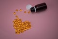 Capsules of cod liver oil arranged in a heart shape on pink background. Royalty Free Stock Photo