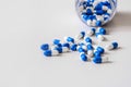 Capsules of the drug, white and blue in color, are scattered from a jar on the table. High-resolution photos. Macro photography