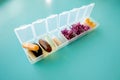 Capsules lie in a pill box on a blue background. Box for packing tablets for a week. Medicine and flowers, alternative medicine Royalty Free Stock Photo