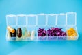 Capsules lie in a pill box on a blue background. Box for packing tablets for a week. Medicine and flowers, alternative medicine Royalty Free Stock Photo