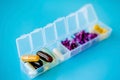Capsules lie in a pill box on a blue background. Box for packing tablets for a week. Medicine and flowers, alternative medicine Royalty Free Stock Photo