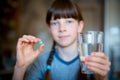 Capsules, pills in one hand, a glass of water in the other. The girl is holding the medicine in front of her. Close-up Royalty Free Stock Photo