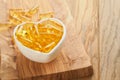 Capsules with Vitamin D, E or Omega 3,6,9 fatty acids in heart shape bowl on old wooden backgrounds. Food supplement oil filled Royalty Free Stock Photo