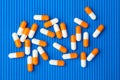 Capsules (pills) orange and white were poured on a blue background. Medical background, template