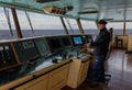 The captain with a blue cap on the bridge of his cargo ship at sea. Royalty Free Stock Photo