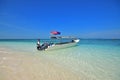 Captain, boat of nearby resort, fine white sand, shallow blue water with cloudless sky at Pulau Lima Besar island, Johor, Malaysia