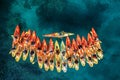 Captain of the kayaking team stands perpendicular in the boat in front of a row of kayaks. Top view