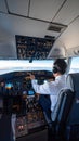 Captain operating the controls in an airplane cockpit with illuminated instrument panels during flight Royalty Free Stock Photo