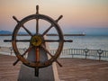 Captains steering wheel or rudder of an old wooden sailing ship in a port at sunset