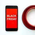 Caption BLACK FRIDAY on red smartphone screen. Concept of sales, online shopping, and e-commerce.