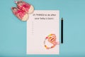 Caption 15 things to do after your baby is born. White A4 sheet on blue background next to baby pink booties and pacifier holder. Royalty Free Stock Photo