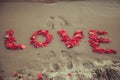 Caption Word Love In The Sand Of The Sea. Love Inscription From The Petals Of Roses.