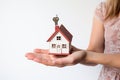 Woman hand holding house model on white background. Real estate concept. Ai generative