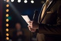 Keynote Speaker on Podium with Script and Microphone in Bright Spotlight at Business Conference