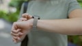 Captivating moment of a woman standing outdoors in the city park, her hands tenderly touching the ticking hands of her wristwatch