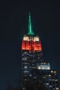 Empire State Building Illuminated in Green, Yellow, and Red Lights Against New York City Sky Royalty Free Stock Photo