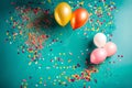 Colourful balloons arranged on a blue coloured table with some poppers for birthday - AI Generated