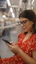 Captivating portrait of a beautiful young hispanic woman donning glasses, engrossed in her phone as she embraces urban city life, Royalty Free Stock Photo