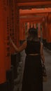 Captivating view of a beautiful hispanic woman in glasses, lost in the mesmerizing walk through the vibrant orange torii gates at