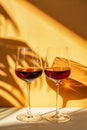 Two glasses with red wine, candid moments, light orange and gold.