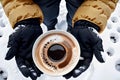 Coffee cup cradled by two gloved hands in snowy outdoor