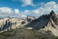 A capture of high and sharp peaks of Dolomites in Italy. Dried grass on the meadow. The sky is full of soft clouds.