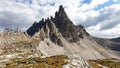 A capture of high and sharp peaks of Dolomites in Italy. Dried grass on the meadow. The sky is full of soft clouds.