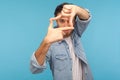 Capture moments. Portrait of inspired creative cameraman in worker denim shirt looking through photo frame Royalty Free Stock Photo