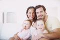 Capturing a blissful family moment. Cropped portrait of a happy family of four sitting close together on a sofa indoors.