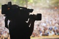 Capturing the excitement. A silhouette of a cameraman filming an event. Royalty Free Stock Photo