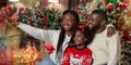 African american family taking Christmas selfie in decorated living room