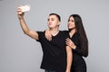 Capturing happy moments together. Happy young loving couple making selfie and smiling while standing against grey background Royalty Free Stock Photo