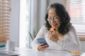 Capturing the Joys of Aging: A Happy Senior Woman Embracing Technology as She Navigates Her Smartphone with Ease from