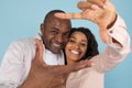 Capturing moments. Close up portrait of black couple making picture frame with fingers, looking at camera and smiling Royalty Free Stock Photo