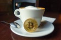 Capuccino and bitcoin gold coin on the table in cafe