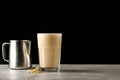 Capuccino in glass isolated on black with carob and pitcher