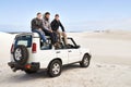 Car, adventure and friends sitting on roof for road trip break, travel and off road drive in sand dune. Relax Royalty Free Stock Photo