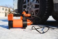 Car air compressor in working position at snow. Self-inflating wheels, automobile tire pressure control.