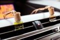 Car air perfume freshener bottles inside the car on car panel. Aromatic liquid in the small bottle
