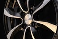 Car alloy wheel close-up of the disc element, curves smooth lines of the wheel spokes, polished front surface. black background,