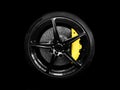 Car alloy wheel and tyre isolated on black background. New alloy wheel with tire and yellow carbon ceramic brakes. Alloy rim