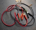 Car battery charging cables in red and black colors on dark grey floor. Royalty Free Stock Photo