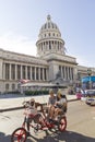 A car-bike with tourists circle in front of the Capitol