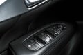 Car black perforated leather interior details of door handle with windows controls and adjustments. Car door handle inside the lux Royalty Free Stock Photo