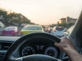 Car on-board view of hand holding steering wheel.