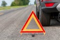 Car breakdown on side of road with warning triangle.