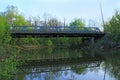 Car bridge across river is reflected in water in calm spring day. Pond in forest Royalty Free Stock Photo